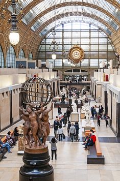 the inside of a train station with people walking around and looking at statues on display