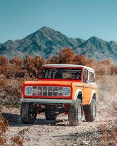 an orange truck driving down a dirt road