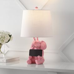 a pink elephant lamp sitting on top of a white table next to a vase with flowers