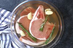 two raw meats in a glass bowl with rosemary garnish