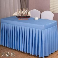 there is a table with a blue cloth on it and a ship in the background