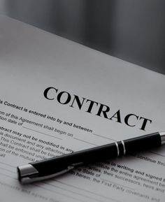 a pen sitting on top of a paper with the word contract written in black ink