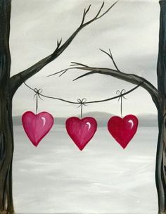 three hearts hanging from a tree branch in front of the ocean with snow on the ground