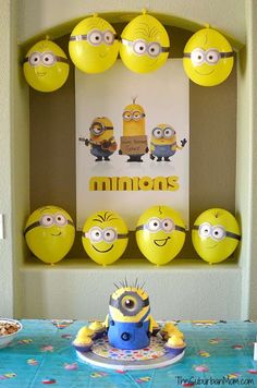 a birthday party with yellow balloons and minion decorations on the wall, including a blue cake