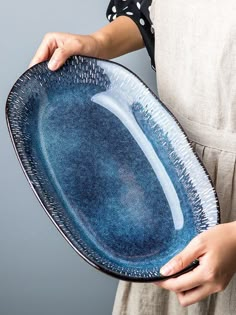 a woman is holding a blue plate in her hands