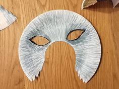 paper mache mask sitting on top of a wooden table next to scissors and other items