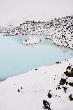 a body of water surrounded by snow covered ground