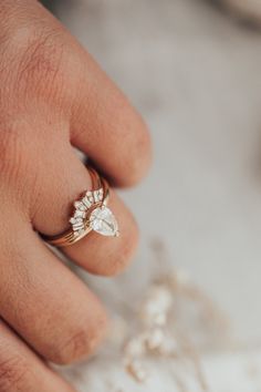 a woman's hand wearing a gold ring with white flowers on the band and a diamond in the middle