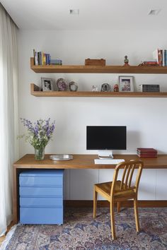 a wooden desk with a computer on top of it next to a blue drawer and chair