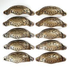 six antique brass drawer pulls on a white background