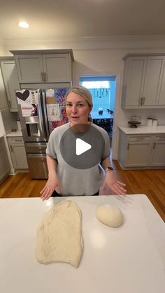 a woman standing in front of a white counter top with two doughnuts on it