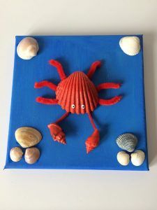 a blue tray with shells and a red crab on it