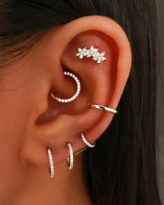 a woman wearing three different types of ear piercings