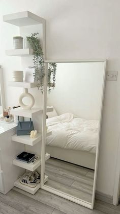 a bedroom with a bed, mirror and plant on the shelf in front of it