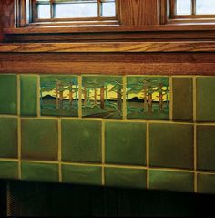 a green tiled wall with trees and mountains in the background, on a wooden mantle