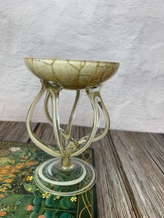 a glass vase sitting on top of a wooden table next to a green and yellow book