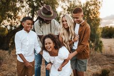 a group of people standing around each other in the middle of a field with trees