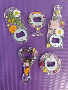 three glass bottle openers with flowers and leaves on them sitting on a purple mat