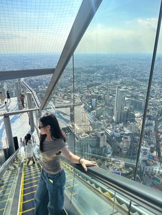 a woman standing on top of a tall building looking down at the cityscape