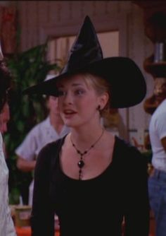 a woman in a witches hat talking to a man