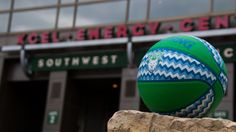 a green and blue ball sitting on top of a rock in front of a building