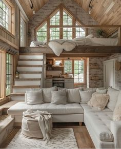 a living room filled with lots of furniture and windows in the ceiling above it is a loft bed that's built into the wall