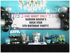 a birthday party with balloons and decorations on the table, including a sign that says hudson bones's rock star 5th birthday party