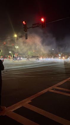 a group of people standing on the side of a road next to a traffic light