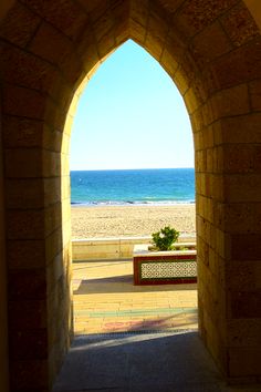 an archway leading to the beach with a potted plant on it and water in the background