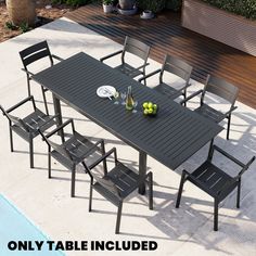 an outdoor dining table with six chairs and two wine glasses on it, next to a swimming pool