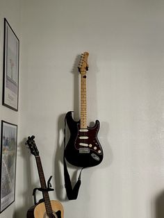 two guitars and a guitar hang on the wall