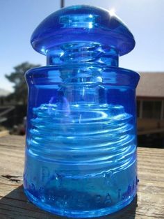 a blue glass container sitting on top of a wooden table next to a house and water tower