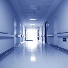 an empty hospital hallway with blue walls and white flooring is seen in this image