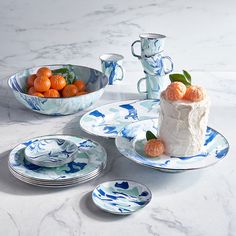 a table topped with plates and bowls filled with oranges next to a bowl of fruit