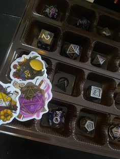 an assortment of chocolates in a tray with stickers on them, sitting on a table