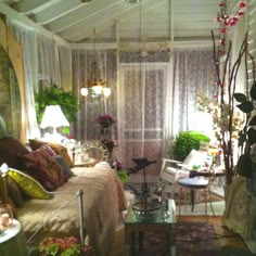 a living room filled with lots of furniture and flowers on the windows sills