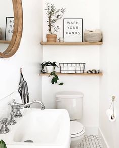 a white bathroom with black and white tile flooring, shelving above the toilet