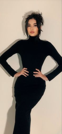 a woman is posing in a black dress