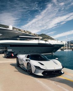 a white sports car parked in front of a large boat