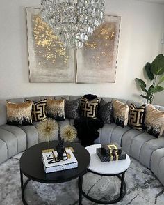 a living room filled with furniture and a chandelier hanging above the couches