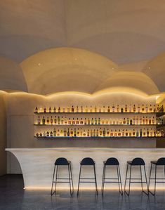 a bar with stools and bottles on the wall