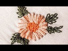 a close up of a flower on a piece of cloth with green and orange trim