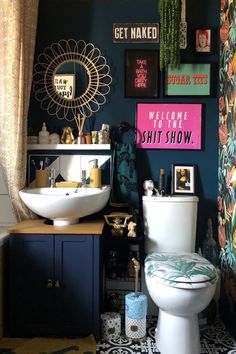 a bathroom with a toilet, sink and pictures on the wall