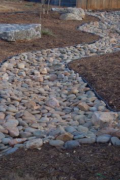 a stone path in the middle of a yard with rocks and gravel on both sides