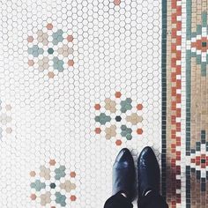 a person wearing black shoes standing in front of a tiled floor with hexagonal tiles