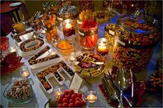 a table filled with lots of different types of desserts and candles on top of it