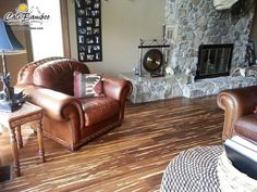 a living room with two leather chairs and a fireplace in the corner, next to a wicker table