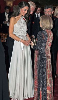 two women standing next to each other in front of an audience at a formal event