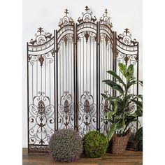 an ornate iron screen with potted plants in front of it on a wooden table