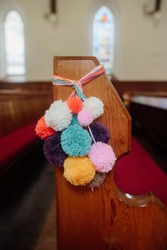 colorful pom - poms hang from the pews of a church